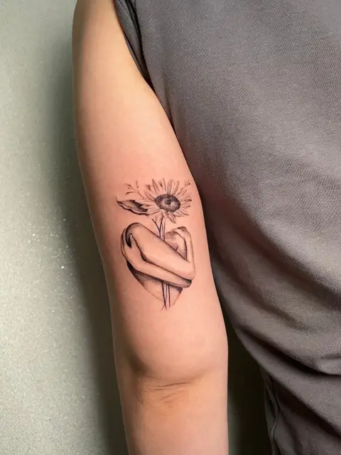 Tatuaggio: figura che abbraccia un girasole, in piccolo, di Francesco - White Garden Tattoo, Roma Colli Aniene